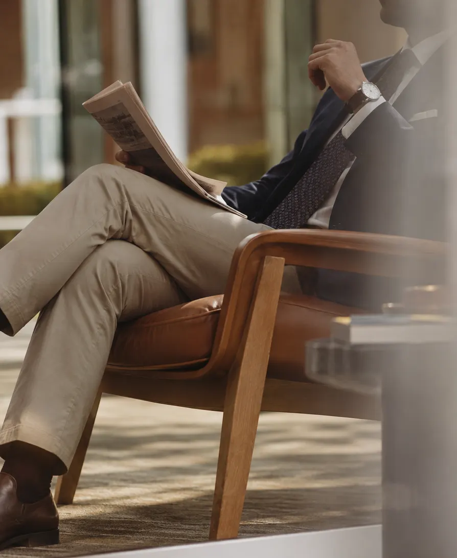 Ejecutivo leyendo en un lounge con luz de tarde.